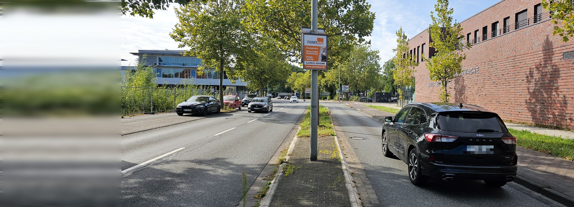 Werberahmen der PrimoBau GmbH mit beleuchteter Plakatfläche an einer Hauptverkehrsstraße in Gütersloh